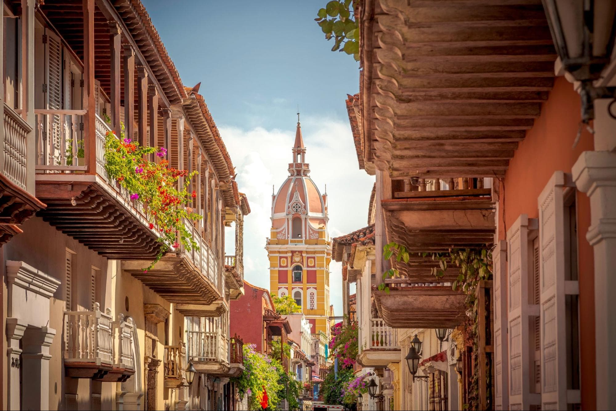 Calle colonial con balcones de colores frente a la catedral de Cartagena